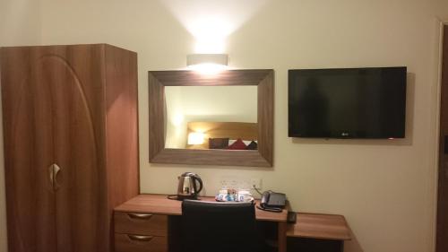 um quarto com uma secretária com um espelho e uma televisão em Gateway Express em Newport