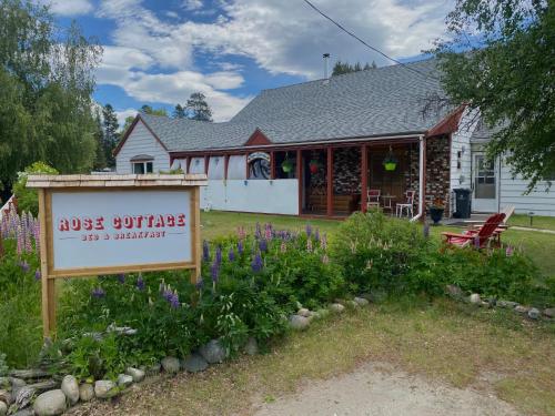 a sign in front of a house with flowers at Rose Cottage Bed & Breakfast in Valemount