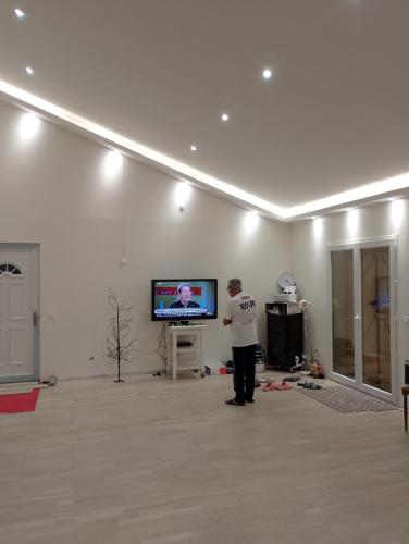 un homme debout devant une télévision dans une pièce dans l'établissement Gite la roche Chalais, à La Roche-Chalais