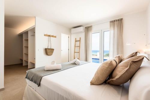 a white bedroom with a large bed and a large window at Villa Atalis in Son Bou