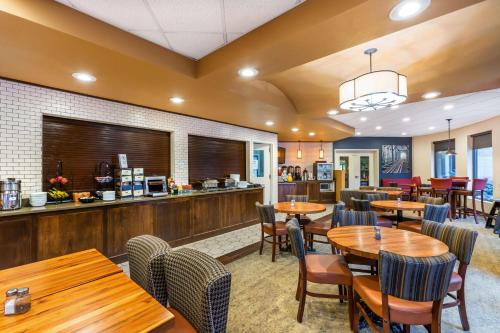 Best Western Premier Helena Great Northern Hotel في هيلينا: مطعم مع طاولات وكراسي خشبية وبار