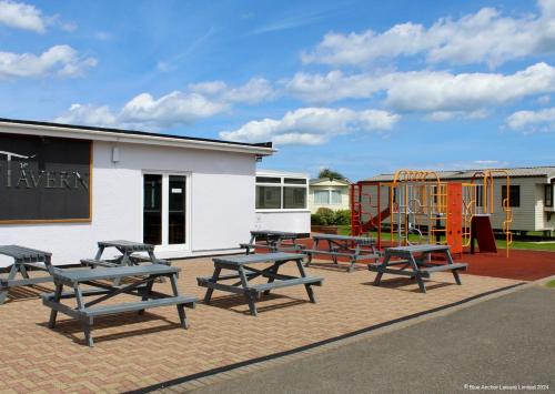 a group of picnic tables next to a playground at Towervans Holiday Park in Mablethorpe
