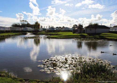 a pond with lilies in the water with houses in the background at Towervans Holiday Park in Mablethorpe