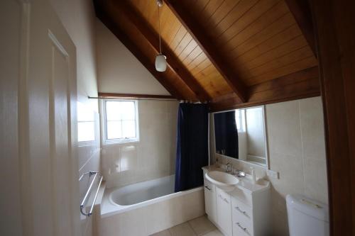 une salle de bain avec une baignoire, un lavabo et un miroir dans l'établissement Kookaburra Cottage 71 Straight St HH, à Hat Head