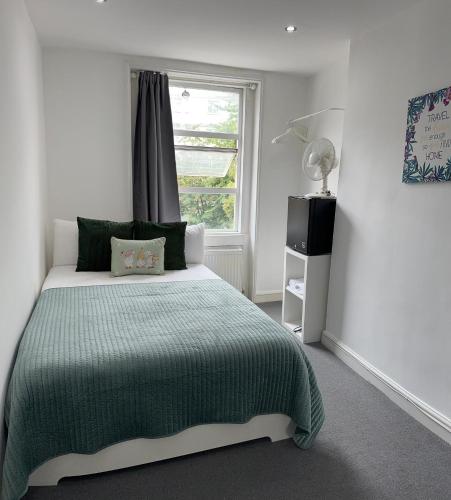 a bedroom with a green bed and a window at LORD MERIT GUEST HOUSE KING'S CROSS GRAYS INN ROAD in London