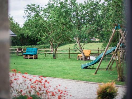 - une aire de jeux avec toboggan et chaises dans la cour dans l'établissement Longère rénovée avec charme, 5 chambres, grand jardin, proche du village, idéale pour 15 pers. - FR-1-410-355, à Saint-Léonard-des-Bois