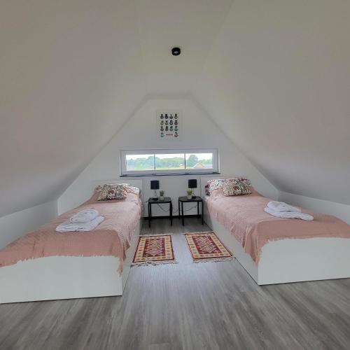 a attic room with two beds and a window at Baltic Barns Berg in Wytowno