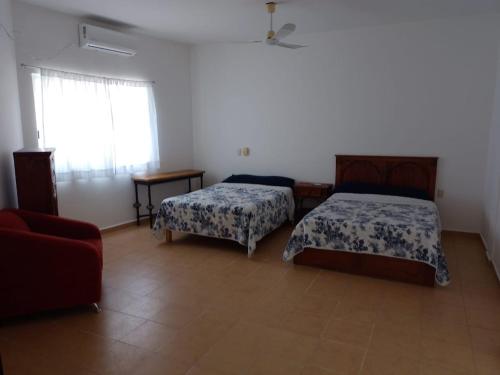 ein Schlafzimmer mit zwei Betten und einer Couch und einem Fenster in der Unterkunft Casa Fefe Huatulco in Tangolunda