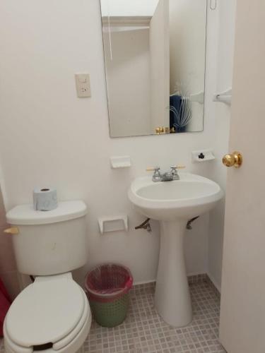 ein Badezimmer mit einer weißen Toilette und einem Waschbecken in der Unterkunft Casa Fefe Huatulco in Tangolunda
