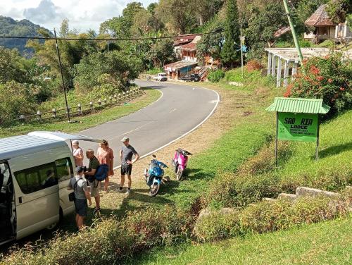 a group of people standing next to a van on a road at Sao Ria Wisata Lodge in Kelimutu