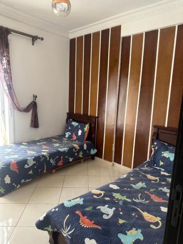 a bedroom with two beds and a wall with stripes at Martil Bel appartement lumineux, situé à seulement proche de la plage, idéal pour les vacances en famille ou entre amis, proche commerces in Martil