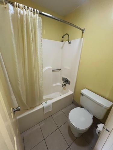 a bathroom with a toilet and a tub and a sink at Antlers Inn in Cuero