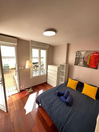 - une chambre dotée d'un grand lit avec des oreillers jaunes et bleus dans l'établissement Superbe appartement terrasse, à Paris
