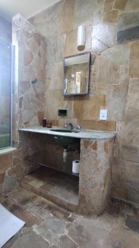 a stone bathroom with a sink and a mirror at Suíte Família vizinha do Palácio de Cristal em Petrópolis! in Petrópolis