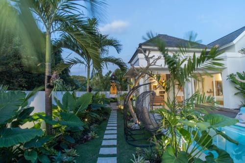 a garden with palm trees and a house at Alas Villa - 3 Bedrooms Private Pool Villa in Nusa Lembongan