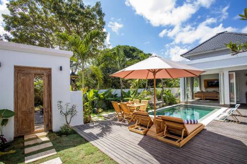 a deck with chairs and an umbrella next to a swimming pool at Alas Villa - 3 Bedrooms Private Pool Villa in Nusa Lembongan