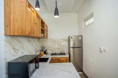 a kitchen with a stainless steel refrigerator and wooden cabinets at Alas Villa - 3 Bedrooms Private Pool Villa in Nusa Lembongan