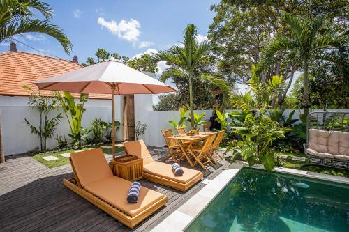 a patio with chairs and an umbrella next to a pool at Alas Villa - 3 Bedrooms Private Pool Villa in Nusa Lembongan