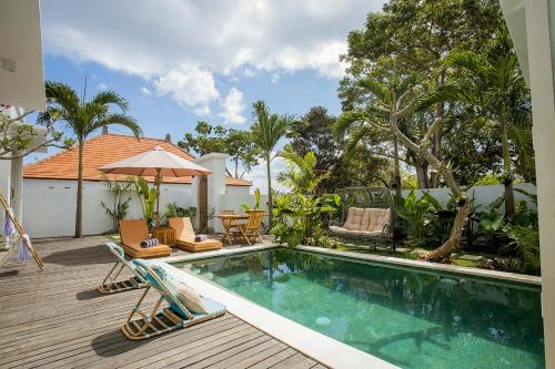 a swimming pool with chairs and an umbrella on a deck at Alas Villa - 3 Bedrooms Private Pool Villa in Nusa Lembongan