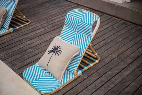 a rocking chair with a palm tree pillow on a deck at Alas Villa - 3 Bedrooms Private Pool Villa in Nusa Lembongan