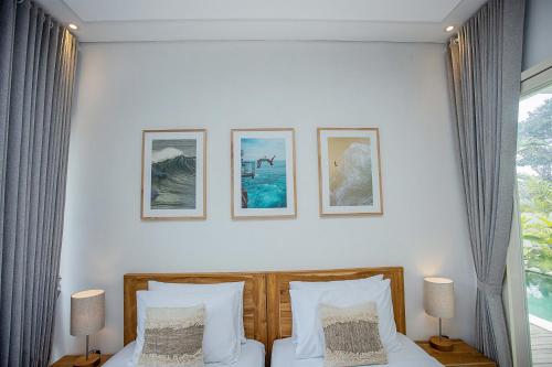a bedroom with a bed with four pictures on the wall at Alas Villa - 3 Bedrooms Private Pool Villa in Nusa Lembongan