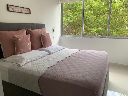 a bed sitting in a room with two windows at Espectacular apartamento en Ricaurte con BBQ in Ricaurte
