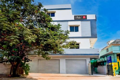 a white building with two garage doors and a tree at Super Collection O SS BLUE INN in Hyderabad