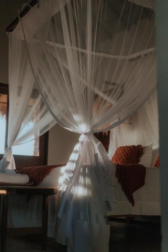 a bedroom with a bed with white curtains at Vila Ronquinha - Arpoador in Tutóia