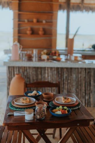 a wooden table with plates of food on it at Vila Ronquinha - Arpoador in Tutóia