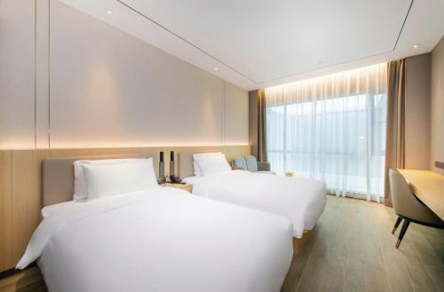 two white beds in a room with a window at 雅庭酒店深圳海岸城南山地铁站店 in Shenzhen