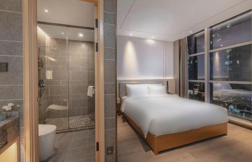 a bedroom with a bed and a bathroom with a shower at 雅庭酒店深圳海岸城南山地铁站店 in Shenzhen