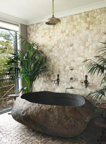 a large rock tub in a bathroom with plants at Culburra Beach House in Culburra Beach