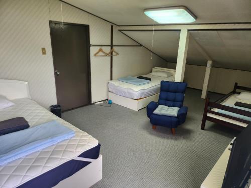 a room with two beds and a blue chair at ロッヂノエル in Seki
