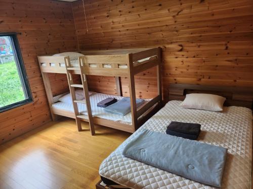 a room with two bunk beds in a log cabin at ロッヂノエル in Seki