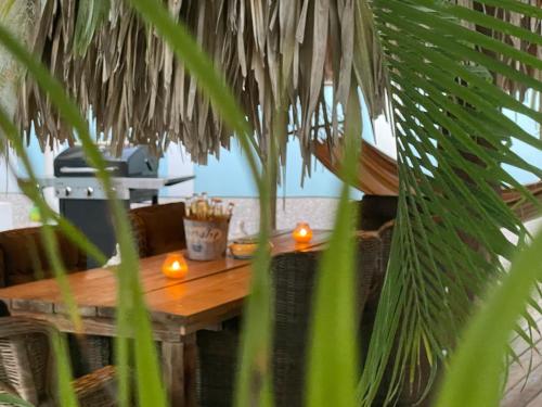 a wooden table with two candles and a palm tree at Villa Blue Curacao in Jan Thiel