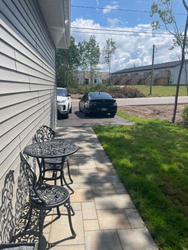 a patio with two chairs and a table and a car at Cozy Basement Apartment in Shediac