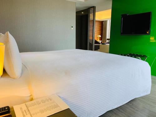 a large white bed in a room with a green wall at CHECK inn SELECT Hualien LinSen in Hualien City