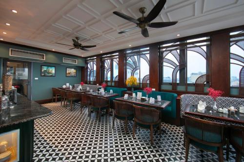 a dining room with tables and chairs and windows at Salute Premium Hotel & Spa in Hanoi