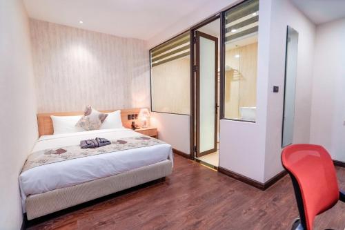 a bedroom with a bed and a red chair at MOMIZI Hotel HAI PHONG in Hai Phong