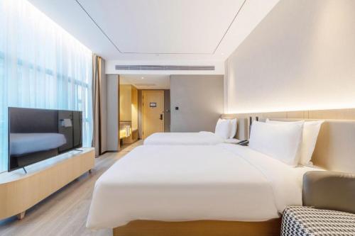 a hotel room with two beds and a flat screen tv at 雅庭酒店深圳海岸城南山地铁站店 in Shenzhen