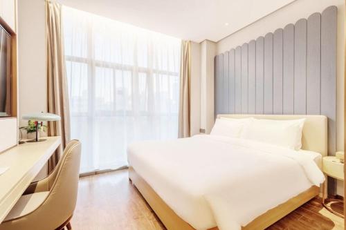 a bedroom with a large white bed and a desk at 雅庭酒店深圳海岸城南山地铁站店 in Shenzhen