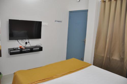 a bedroom with a bed with a tv on the wall at ALAYA ROOMS in Tiruchchirāppalli