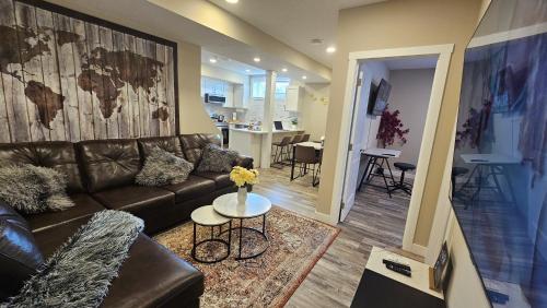 a living room with a leather couch and a table at Luxury Basement Suite with 2 Bedrooms, 2 Queen Beds, Free Wi-Fi, and Free Parking in Calgary