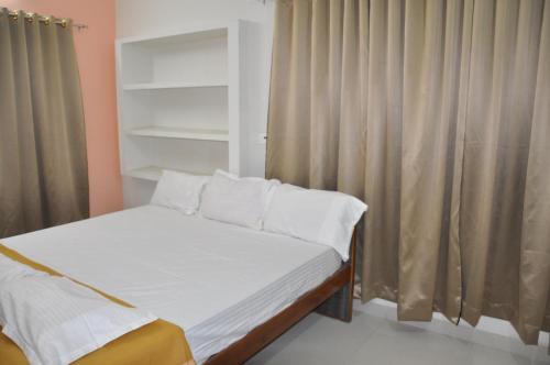 a bed with white sheets and pillows in a bedroom at ALAYA ROOMS in Tiruchchirāppalli