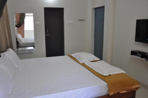 a bedroom with a large white bed with a mirror at ALAYA ROOMS in Tiruchchirāppalli