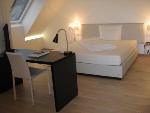 a bedroom with a bed and a desk with a lamp at City Hotel in Linz