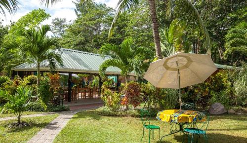 a table with an umbrella and chairs in a yard at La Diguoise in La Digue