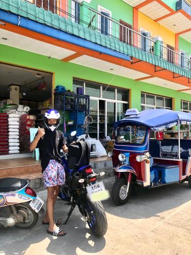 a woman standing next to a motorcycle and a car at Baansrisuthum in Don Sak