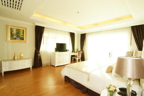 a bedroom with a bed and a desk and a television at LK Miracle Suite - SHA Extra Plus in Pattaya South
