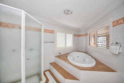 a white bathroom with a tub and a shower at Surfers Reflections Amazing views from your spa! in Gold Coast